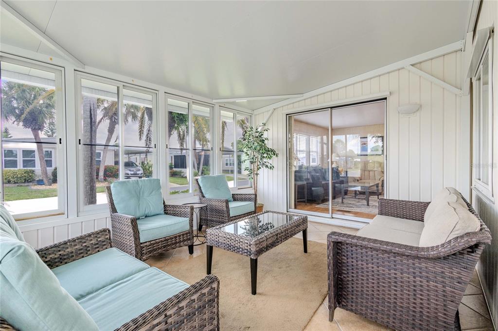 A sunroom features wicker furniture, a glass-top coffee table, and sliding glass doors to outside — 2100 KINGS HIGHWAY UNIT 683, PORT CHARLOTTE, FL