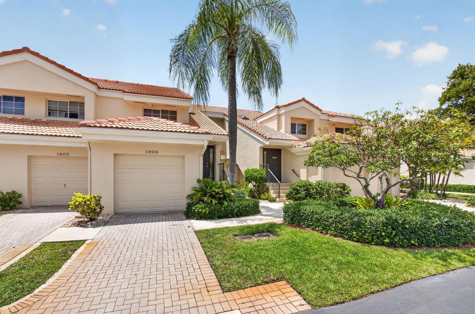 A two-story townhouse exterior features a paved driveway, a palm tree, and landscaped greenery — 17276 Boca Club Boulevard # 1805, Boca Raton FL 33487, BOCA RATON, FL