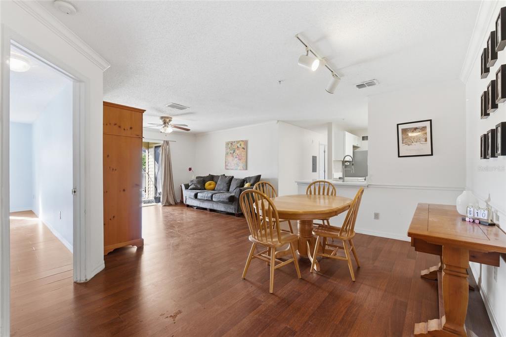 An open-concept living and dining area features wood flooring, a wooden table, and a sofa — 1950 SUMMER CLUB DRIVE UNIT 0214, OVIEDO, FL