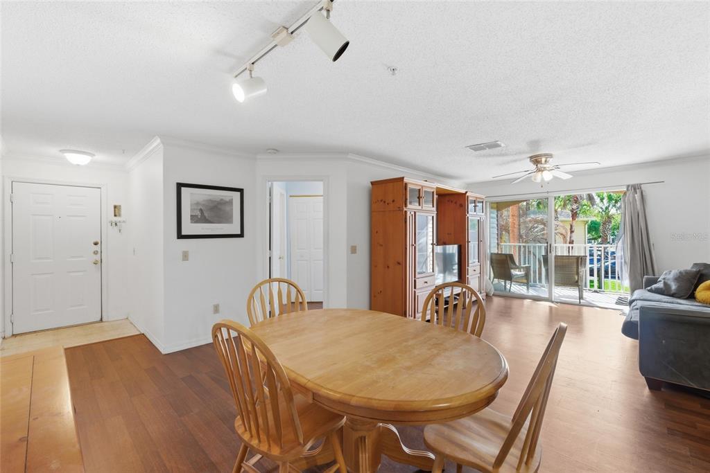 A dining area with a wooden table and chairs opens to a balcony with seating — 1950 SUMMER CLUB DRIVE UNIT 0214, OVIEDO, FL