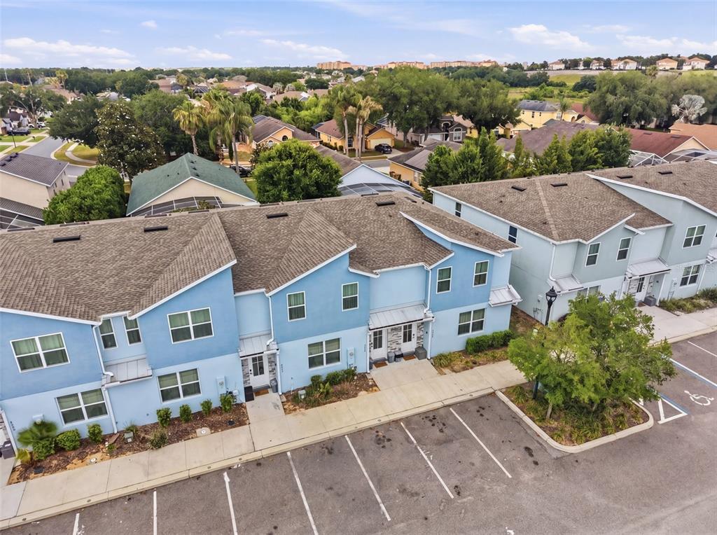 An aerial view shows a blue multi-unit townhouse building with a parking lot in front — 7997 FORMOSA VALLEY PLACE, KISSIMMEE, FL