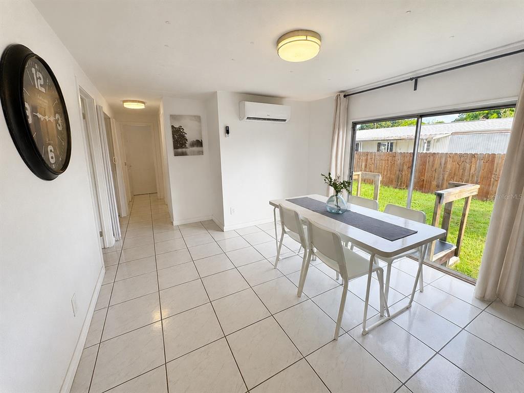 A dining room with white tile floors, a table, and a sliding glass door to a yard — 6931 POMPEII ROAD, ORLANDO, FL