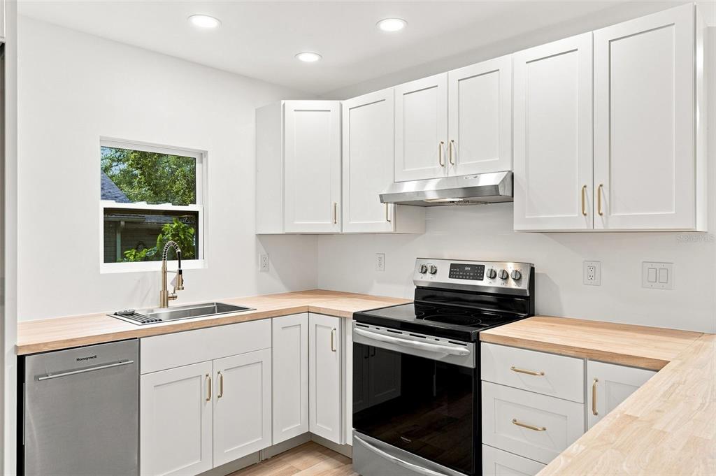 A kitchen with white cabinets, light wood countertops, stainless steel appliances, and a window — 1468 19TH STREET, SARASOTA, FL