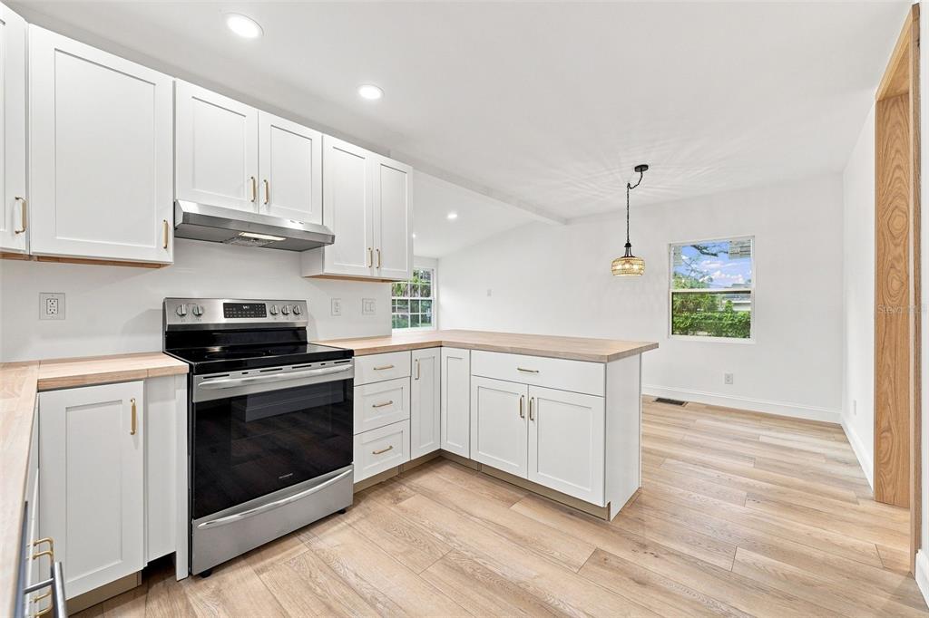A kitchen features white cabinets, light wood countertops, stainless steel appliances, and light wood flooring — 1468 19TH STREET, SARASOTA, FL
