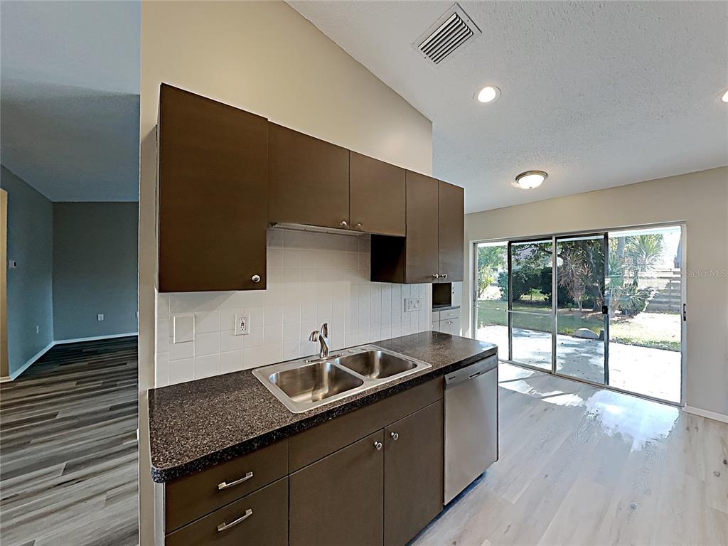 A kitchen features dark brown cabinets, a double-basin sink, dark countertops, and a sliding glass door — 3205 40TH STREET W, BRADENTON, FL
