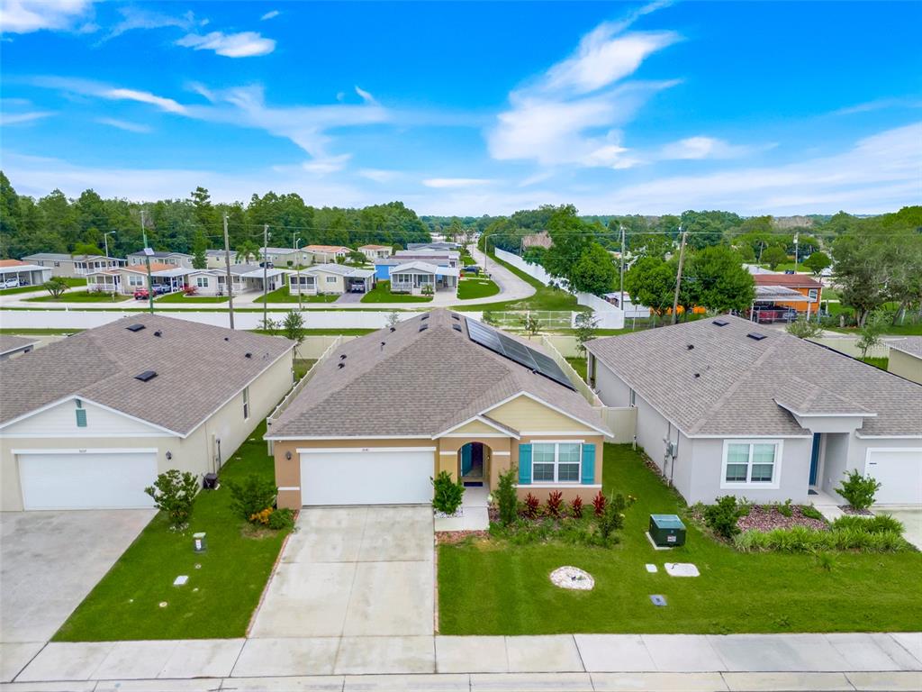 An aerial view shows a tan suburban house with solar panels and a concrete driveway — 3041 TOBAGO DRIVE, HAINES CITY, FL