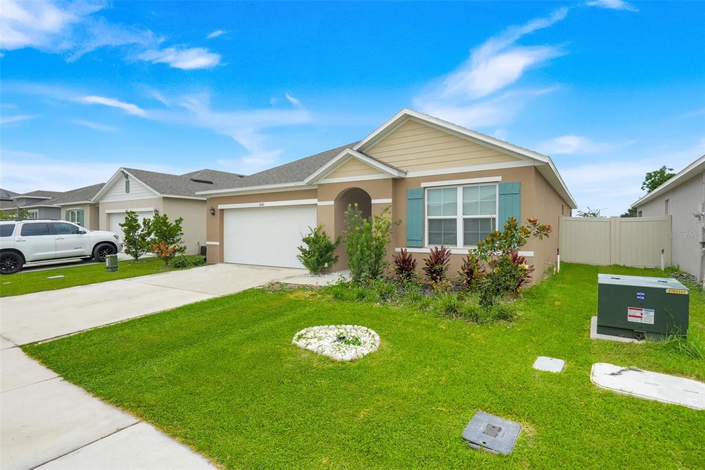 A single-story suburban house with a tan exterior, white garage door, and green lawn — 3041 TOBAGO DRIVE, HAINES CITY, FL