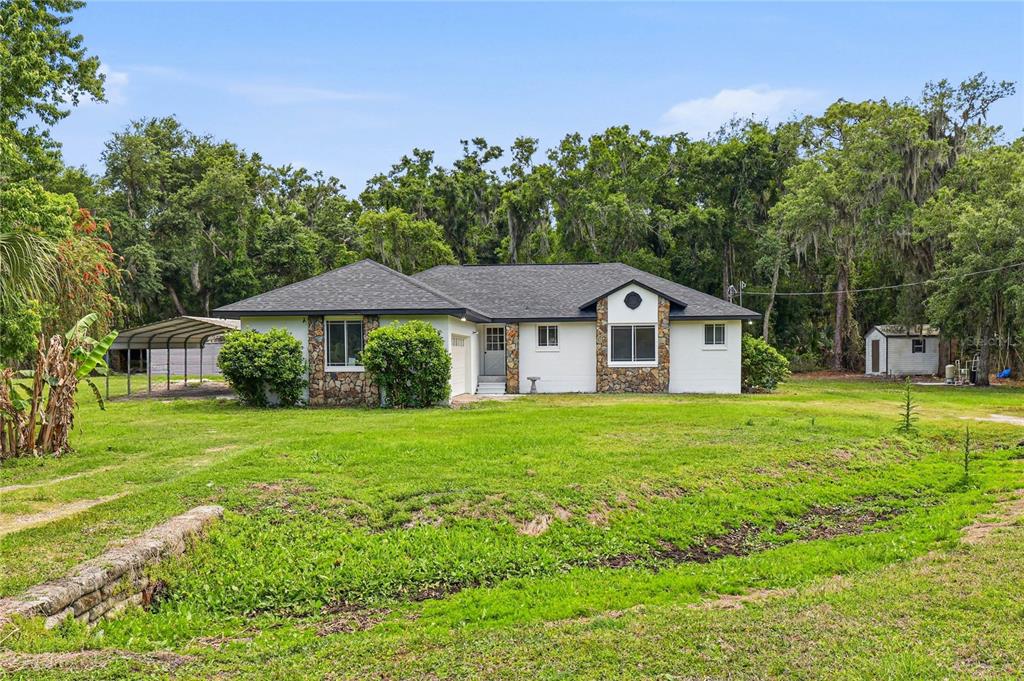 A single-story house with white siding and stone accents sits on a grassy lot — 403 WENDEL AVENUE, LITHIA, FL