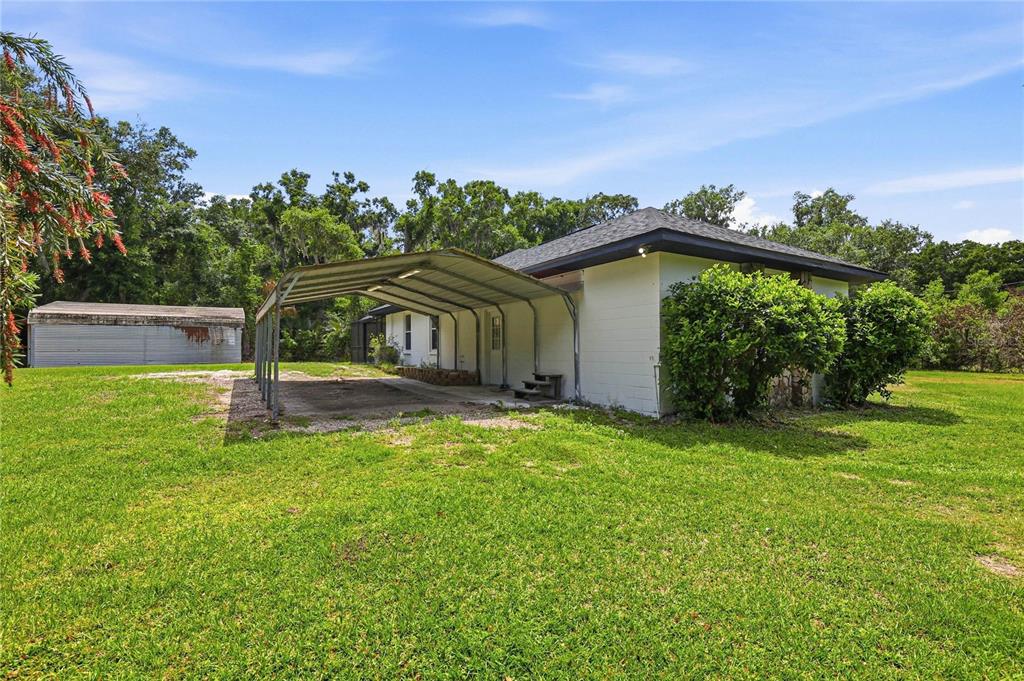 A white house with a metal carport stands on a large, grassy lot — 403 WENDEL AVENUE, LITHIA, FL