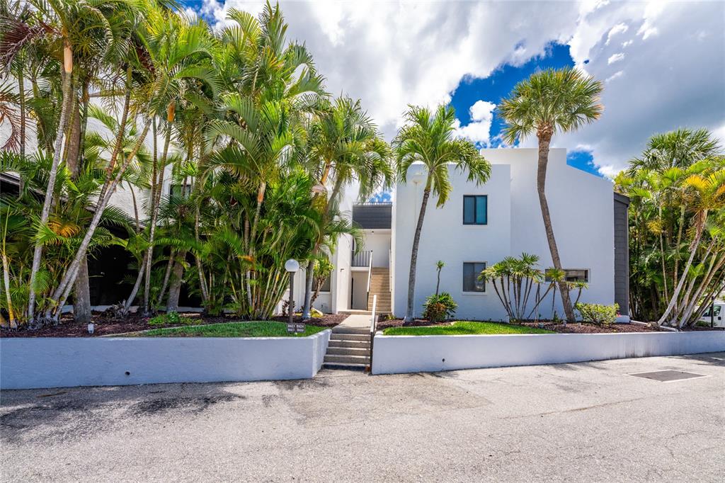 A white multi-story apartment building is surrounded by palm trees and a paved parking lot — 2955 N BEACH ROAD UNIT B-614, ENGLEWOOD, FL