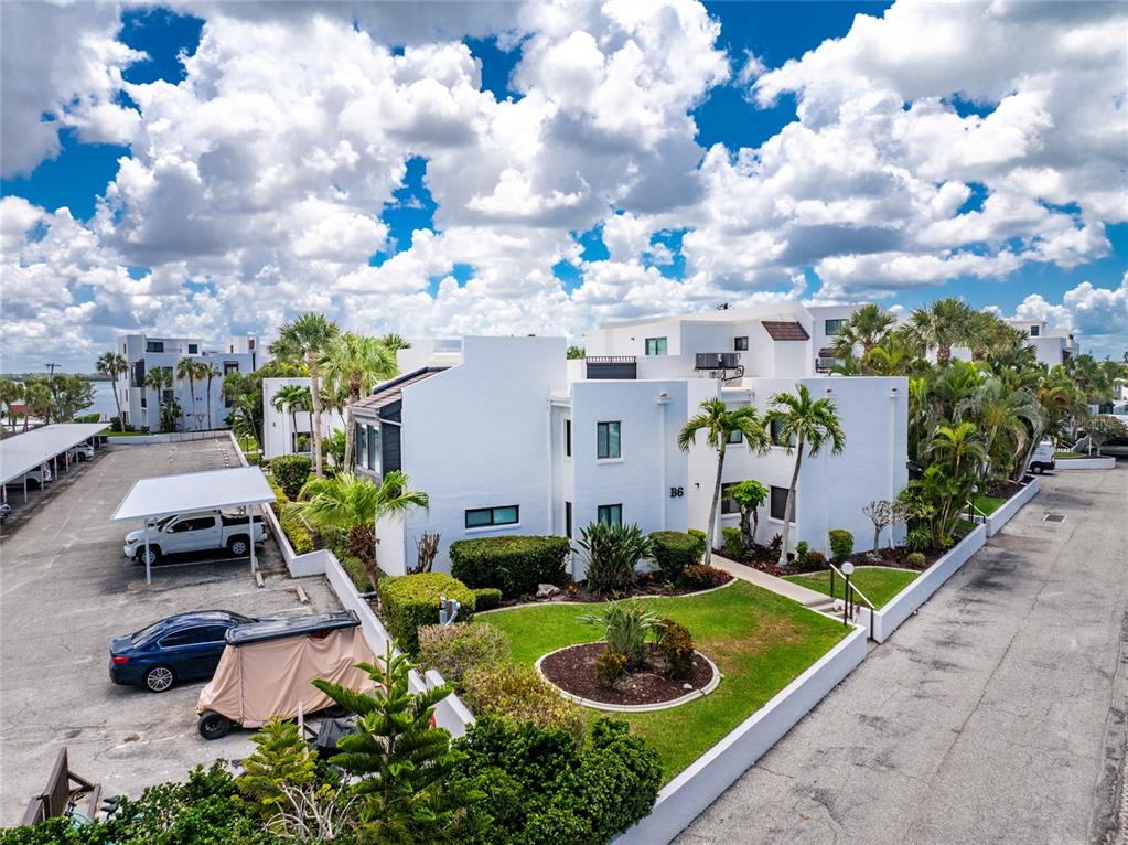 An exterior view of a white multi-story apartment building with a parking lot and landscaping — 2955 N BEACH ROAD UNIT B-614, ENGLEWOOD, FL