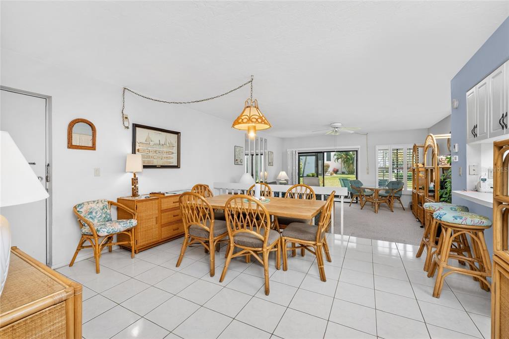 A dining area with wicker furniture, tile flooring, and a view into the living room — 2955 N BEACH ROAD UNIT B-614, ENGLEWOOD, FL