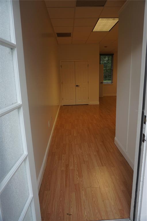 An interior view shows a hallway with light wood-look flooring leading toward double doors — 9111 SW 91ST TERRACE, GAINESVILLE, FL