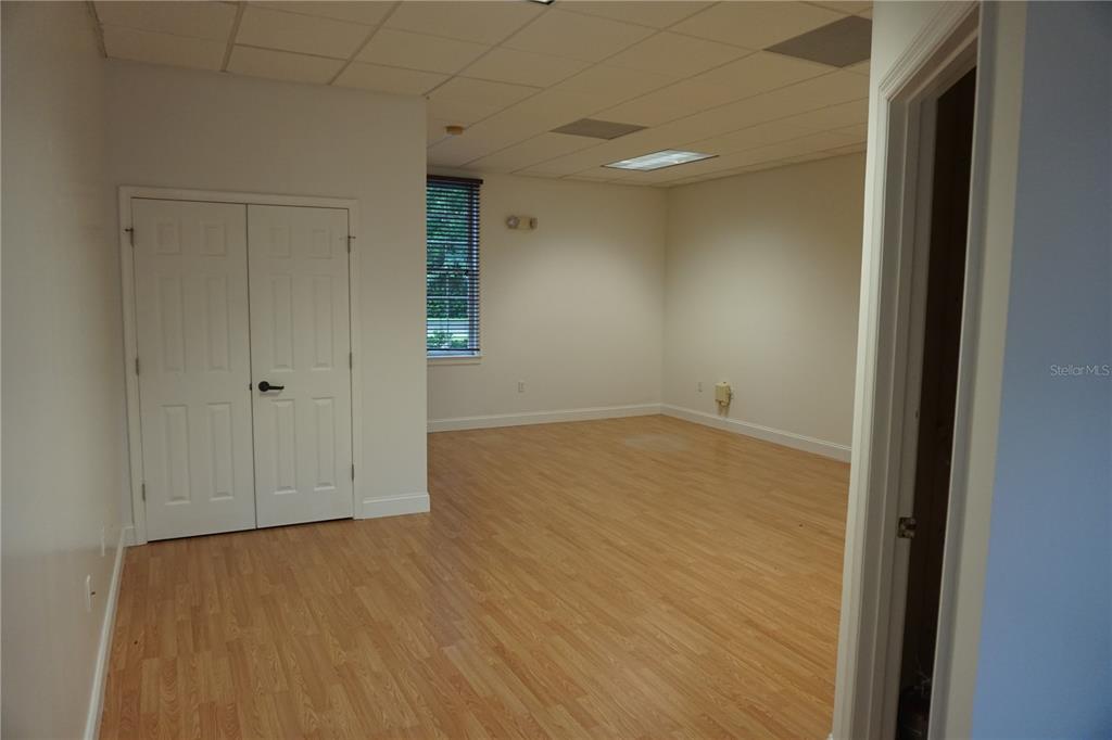 An empty office space features light wood-look flooring, white walls, and a drop ceiling — 9111 SW 91ST TERRACE, GAINESVILLE, FL