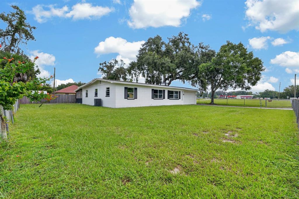 A white, single-story house with a large grassy yard and mature trees — 7 JEANETTE DRIVE, DELAND, FL