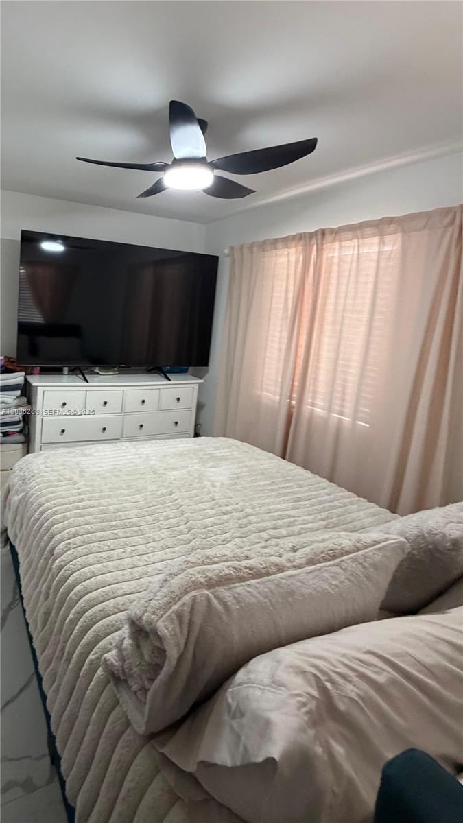 A bedroom features a bed with a textured comforter, a white dresser, and a television — 4161 NE 17th Ave, Pompano Beach FL 33064, POMPANO BEACH, FL