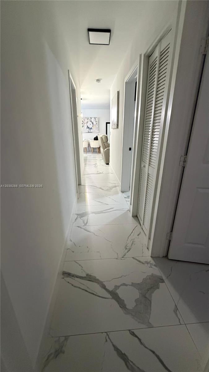 A narrow hallway features white marble-look tile flooring and white walls — 4161 NE 17th Ave, Pompano Beach FL 33064, POMPANO BEACH, FL