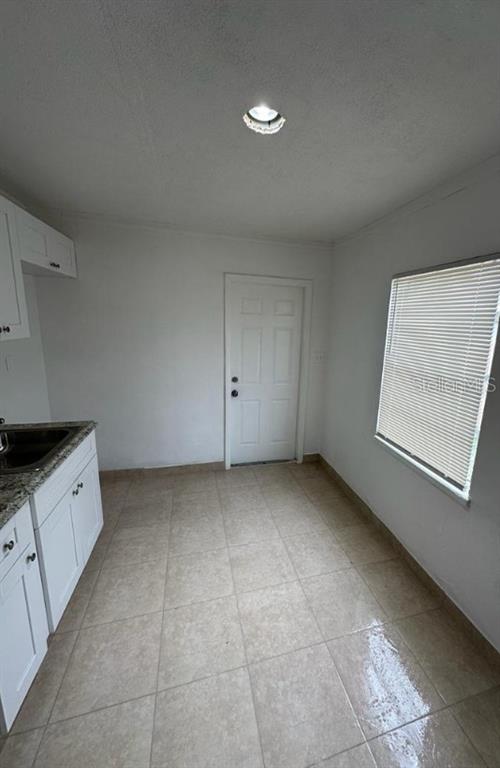 A kitchen with white cabinets, granite countertops, tile flooring, and a door leading outside — 1238 HERSCHELL STREET, LAKELAND, FL