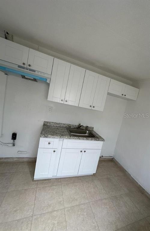 A small kitchen features white cabinets, a granite countertop, and a stainless steel sink — 1238 HERSCHELL STREET, LAKELAND, FL