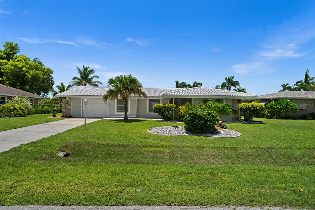 A single-story house with a white roof, beige exterior, and a front lawn — 4102 SE 1ST PLACE, CAPE CORAL, FL