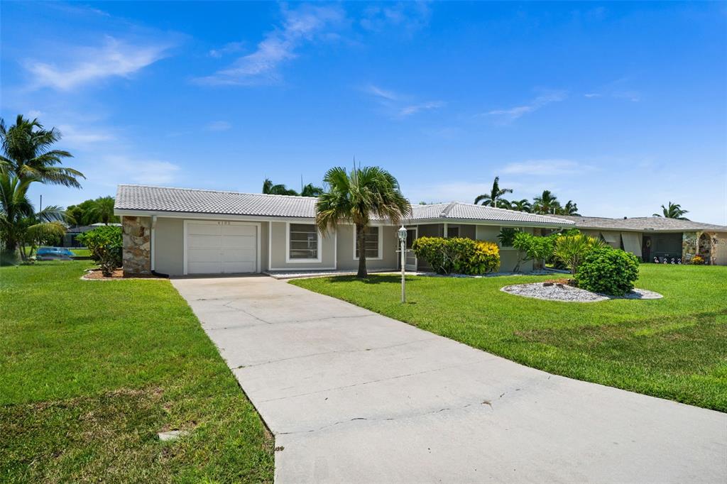 A single-story house with a concrete driveway, a one-car garage, and a palm tree — 4102 SE 1ST PLACE, CAPE CORAL, FL