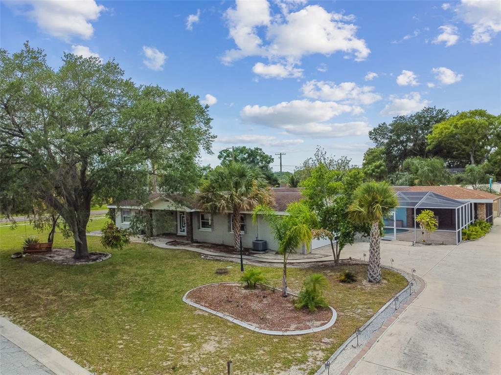 A single-story house with a screened-in pool area, palm trees, and a large front yard — 1302 BRANDONWOOD DRIVE, BRANDON, FL