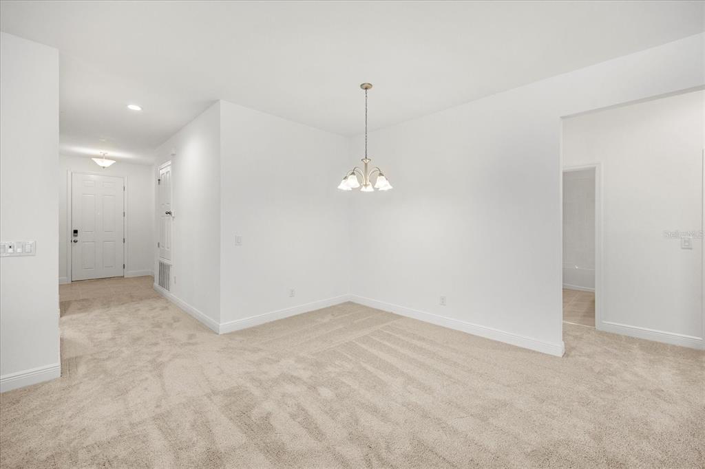 A dining area with beige carpet, white walls, and a hanging light fixture — 7991 SYRACUSE DRIVE, CLERMONT, FL