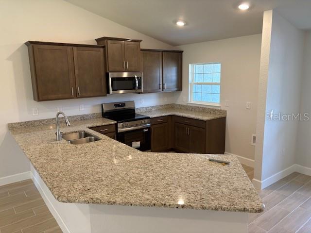 A kitchen features brown cabinets, granite countertops, a stainless steel microwave, and a corner sink — 6770 SW 179TH AVENUE ROAD, DUNNELLON, FL