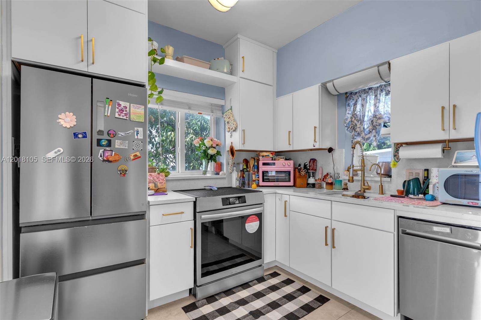 A kitchen features white cabinets, stainless steel appliances, a checkered rug, and light blue walls — 3151 NW Flagler Ter, Miami FL 33125, MIAMI, FL