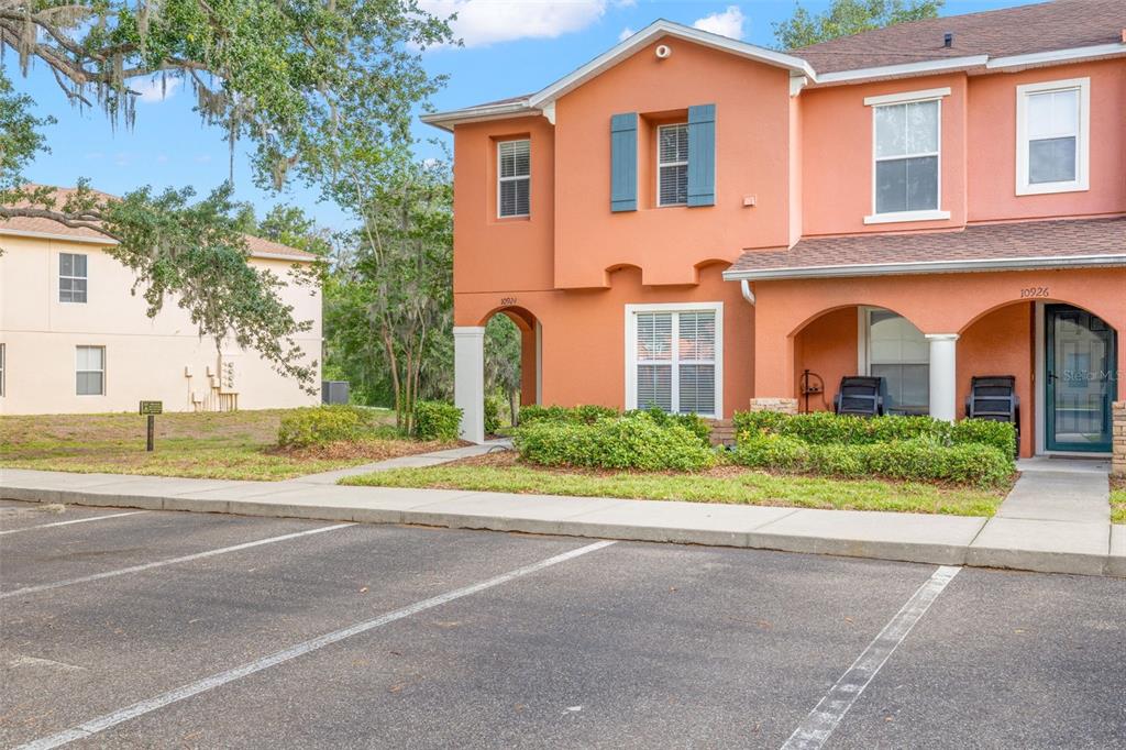 An exterior view of a two-story orange townhouse with a parking lot in front — 10924 JOHANNA AVENUE, RIVERVIEW, FL