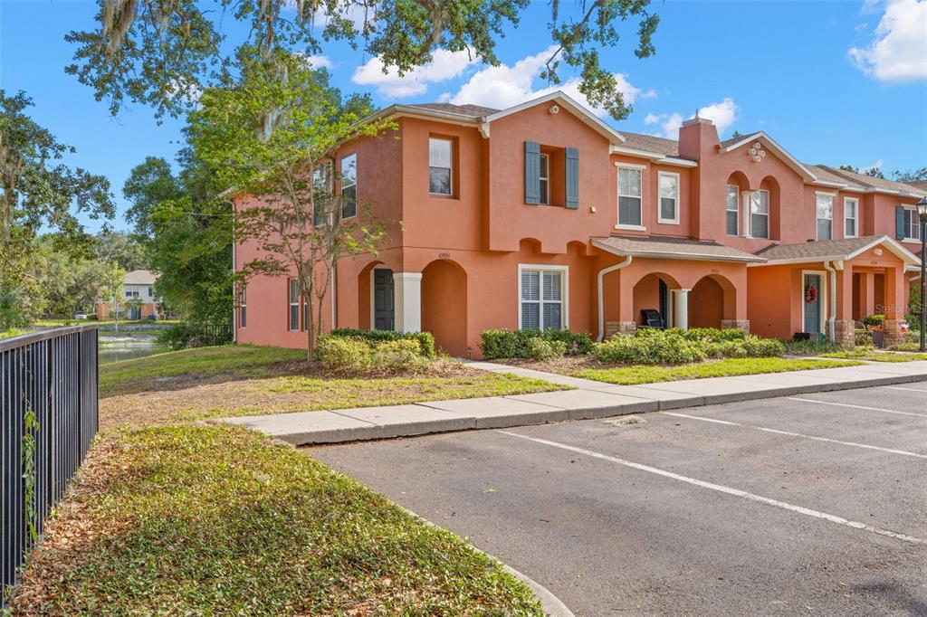 A two-story orange stucco townhouse with a parking lot in the foreground — 10924 JOHANNA AVENUE, RIVERVIEW, FL