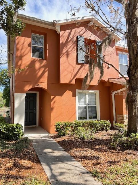 A two-story orange stucco townhouse features a dark front door and a concrete walkway — 10924 JOHANNA AVENUE, RIVERVIEW, FL