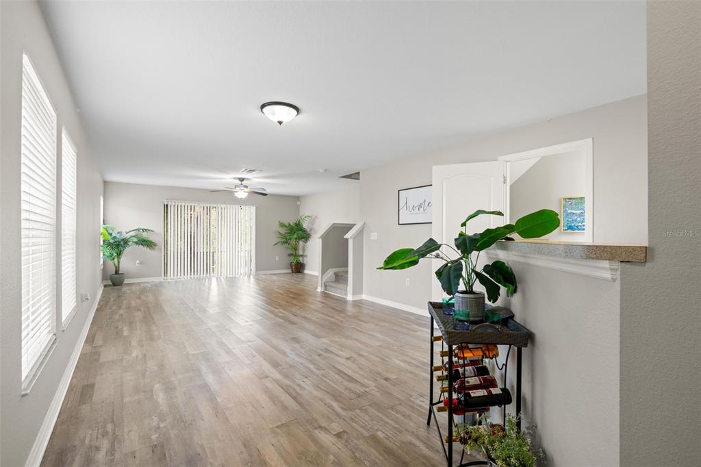 An open living area features wood-look flooring, a ceiling fan, and a staircase — 10924 JOHANNA AVENUE, RIVERVIEW, FL