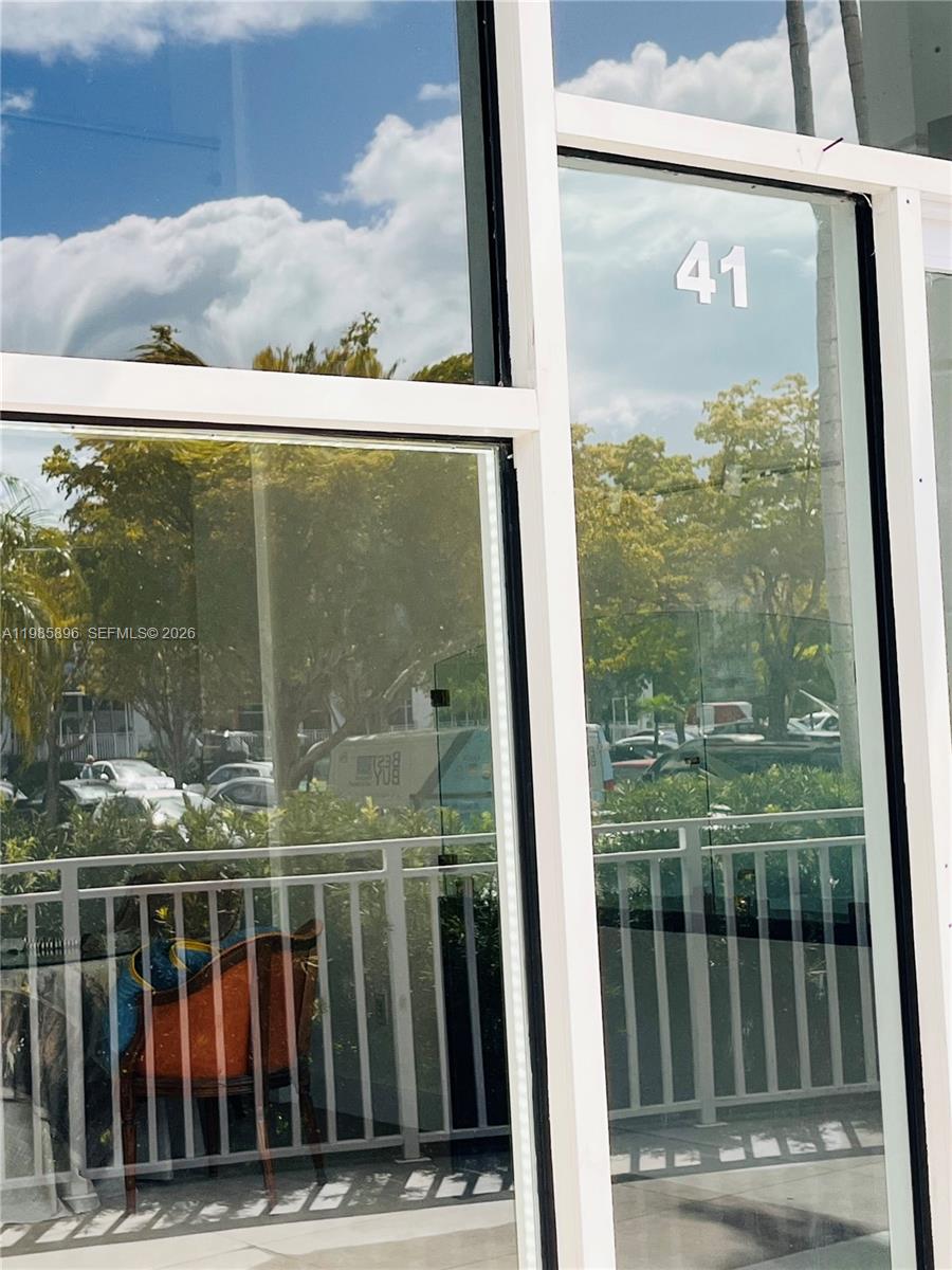 A view through a glass door shows a balcony with a railing and furniture — 260 Crandon Blvd # C41, Key Biscayne FL 33149, KEY BISCAYNE, FL