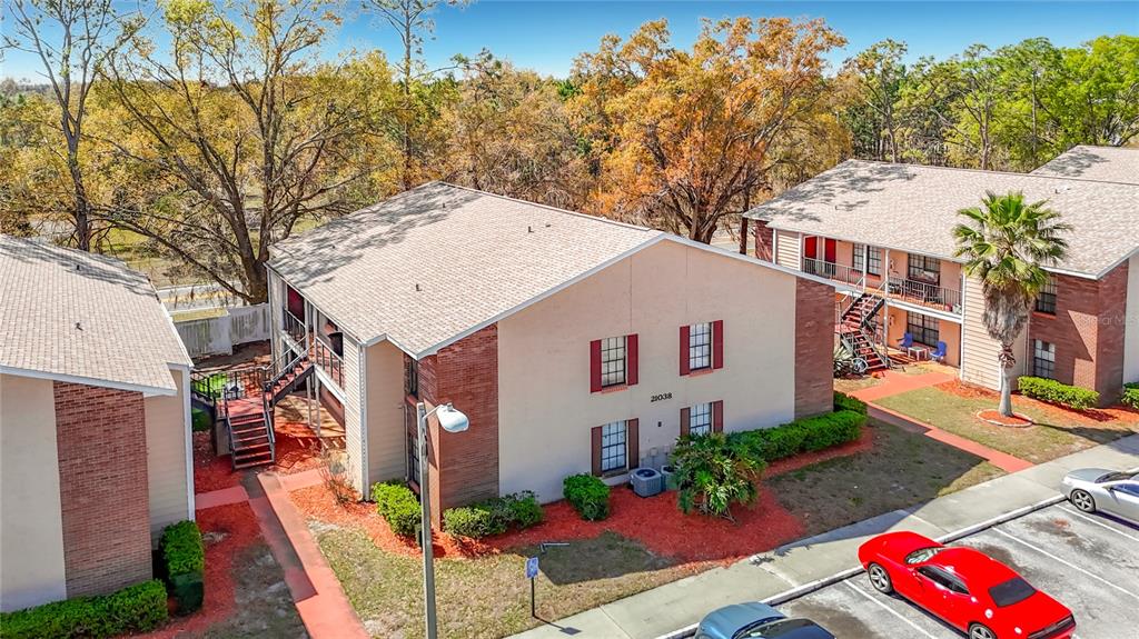 An aerial view shows two multi-story apartment buildings with brick accents and surrounding landscaping — 21038 VOYAGER BOULEVARD UNIT 8, LAND O LAKES, FL