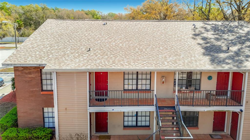An exterior view of a two-story apartment building with red doors and metal staircases — 21038 VOYAGER BOULEVARD UNIT 8, LAND O LAKES, FL