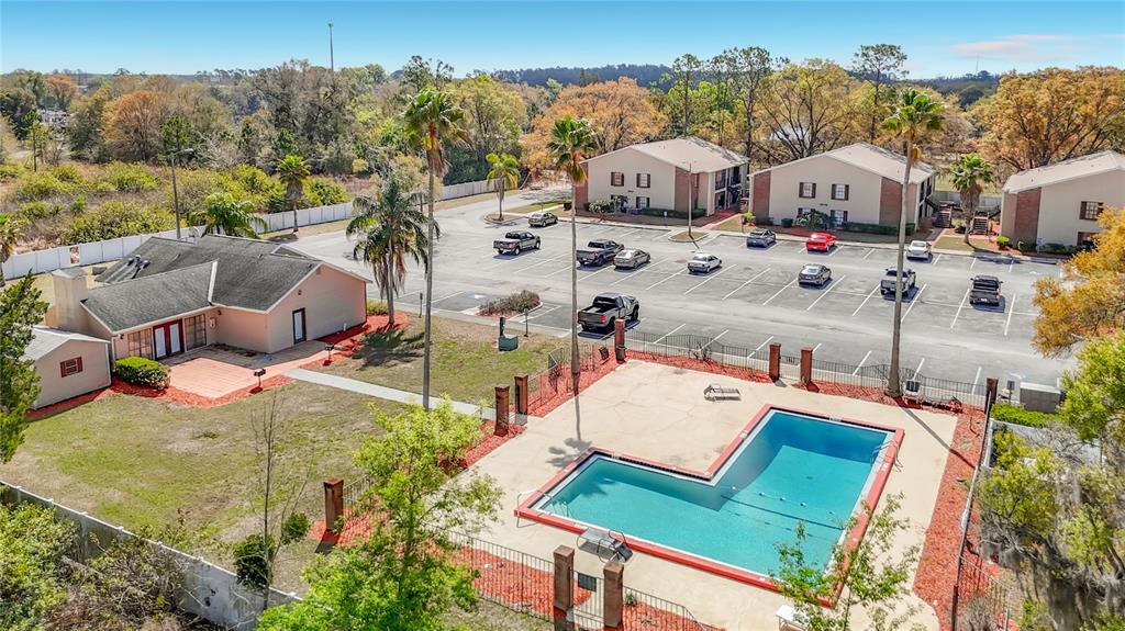 An aerial view shows an apartment complex with a swimming pool, parking lot, and clubhouse — 21038 VOYAGER BOULEVARD UNIT 8, LAND O LAKES, FL
