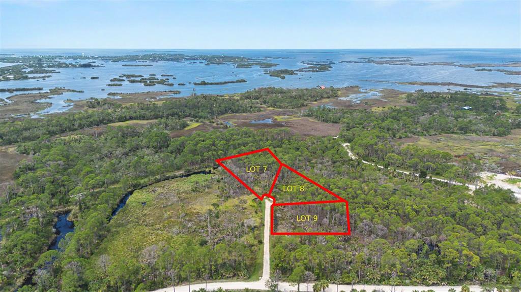 An aerial view shows three outlined land lots surrounded by trees and coastal wetlands — Lot 7 SW 104 STREET, CEDAR KEY, FL