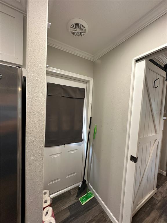 A kitchen area features a white door with a dark shade, a broom, and a sliding door — 16540 SUNSHINE AVENUE, CLERMONT, FL
