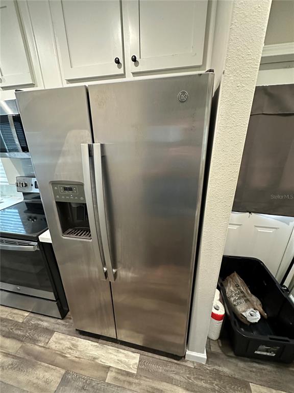 A stainless steel side-by-side refrigerator stands in a kitchen next to a black stove — 16540 SUNSHINE AVENUE, CLERMONT, FL