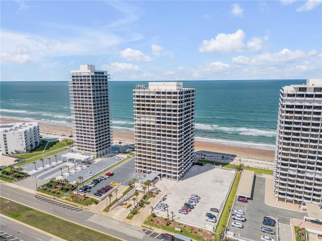 An aerial view shows three tall residential buildings situated along a sandy beach and ocean — 2900 N ATLANTIC AVENUE UNIT 2106, DAYTONA BEACH, FL