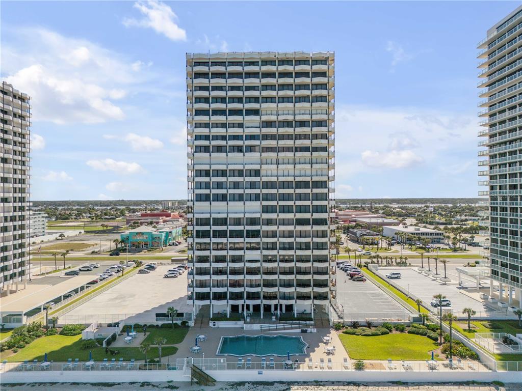An aerial view of a tall beachfront condominium building with a swimming pool and parking — 2900 N ATLANTIC AVENUE UNIT 2106, DAYTONA BEACH, FL