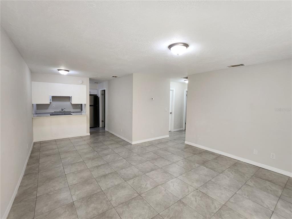 An open-concept living area features gray tile flooring, white walls, and a small kitchen nook — 5200 SE 31ST STREET UNIT 1-4, OCALA, FL