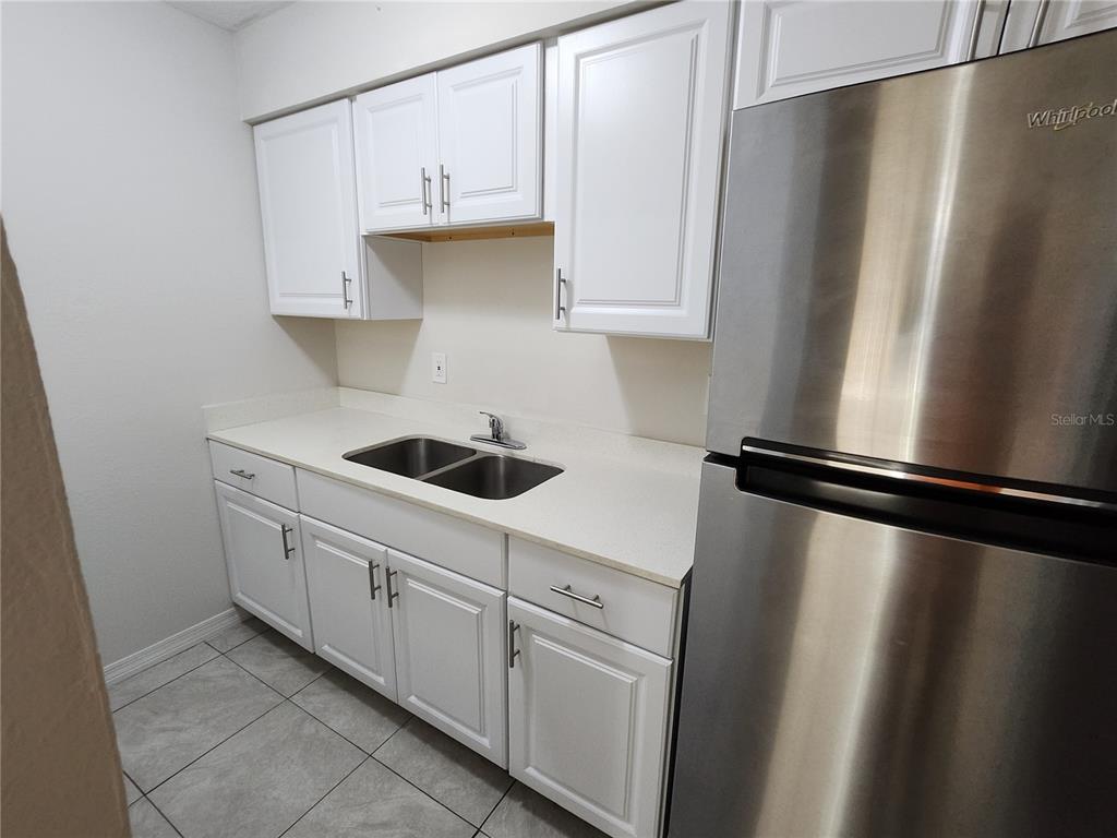 A kitchen features white cabinets, a stainless steel refrigerator, and a double-basin sink — 5200 SE 31ST STREET UNIT 1-4, OCALA, FL