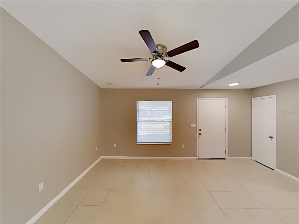 A room with beige walls, tile flooring, a ceiling fan, a window, and two doors — 4128 SUNNY LAND DRIVE, LAKELAND, FL