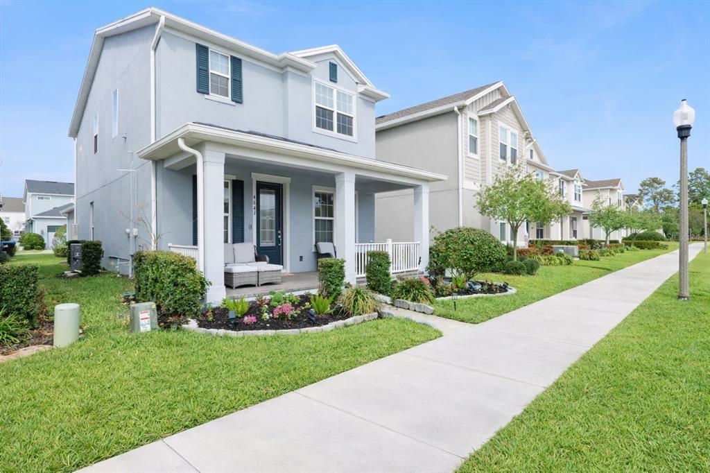 A light blue two-story house with a front porch and a sidewalk in the foreground — 4642 PRAIRIE CREEK STREET, WINTER GARDEN, FL