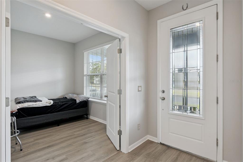 An entryway with a white front door leads into a room featuring wood-look flooring — 4642 PRAIRIE CREEK STREET, WINTER GARDEN, FL