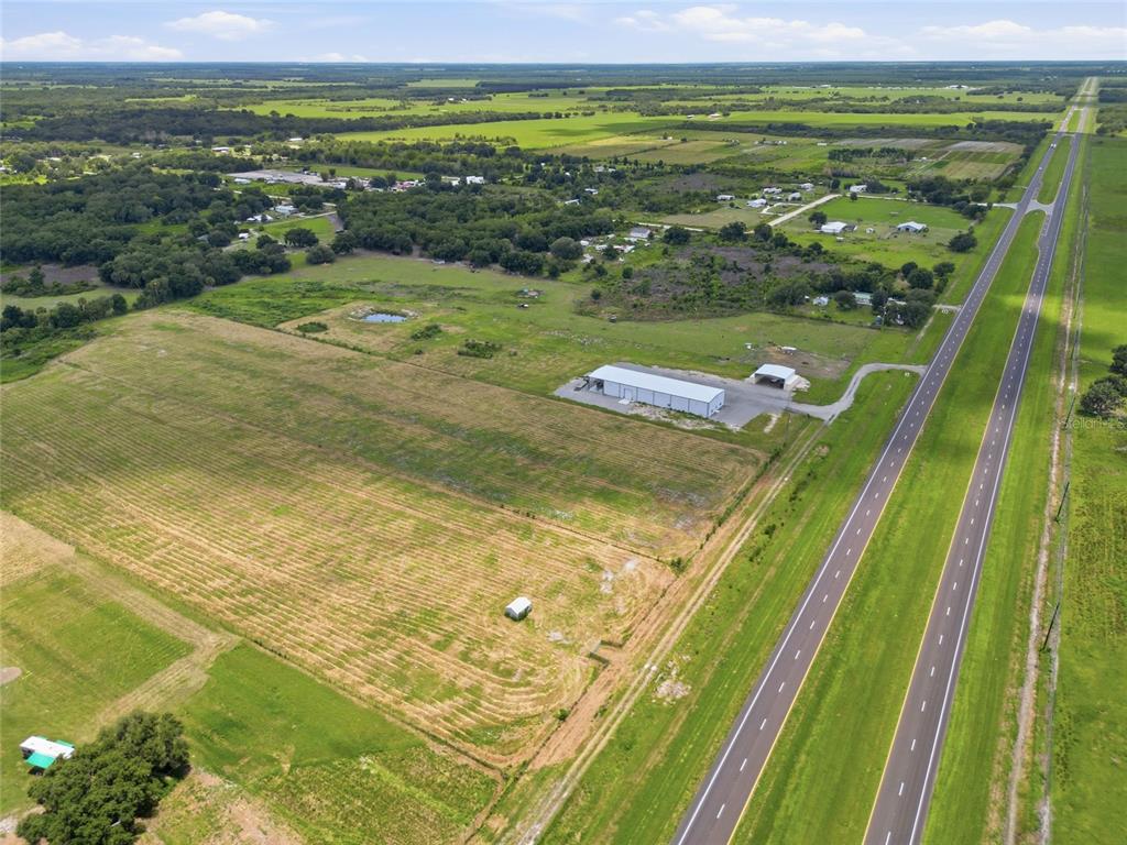 An aerial view shows a large rural property with a warehouse building beside a highway — S US HWY 17, ZOLFO SPRINGS, FL