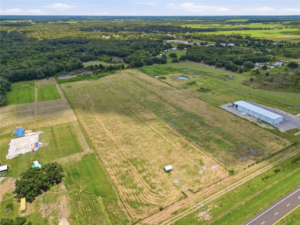 An aerial view shows a large, grassy field with a small shed and nearby buildings — S US HWY 17, ZOLFO SPRINGS, FL