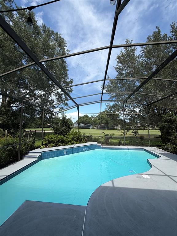 A swimming pool with a blue tiled wall sits inside a screened-in patio enclosure — 2435 SWEETWATER COUNTRY CLUB PLACE DRIVE, APOPKA, FL